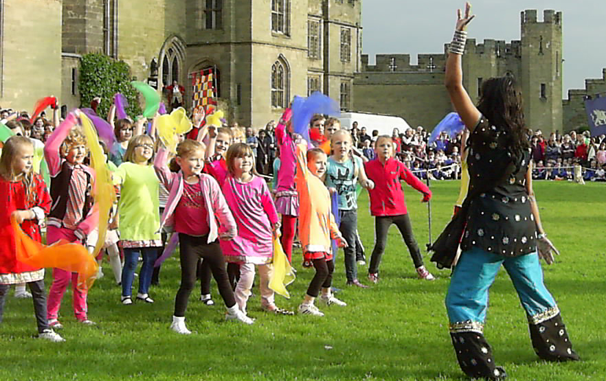 School children performing indian dancing with teacher
