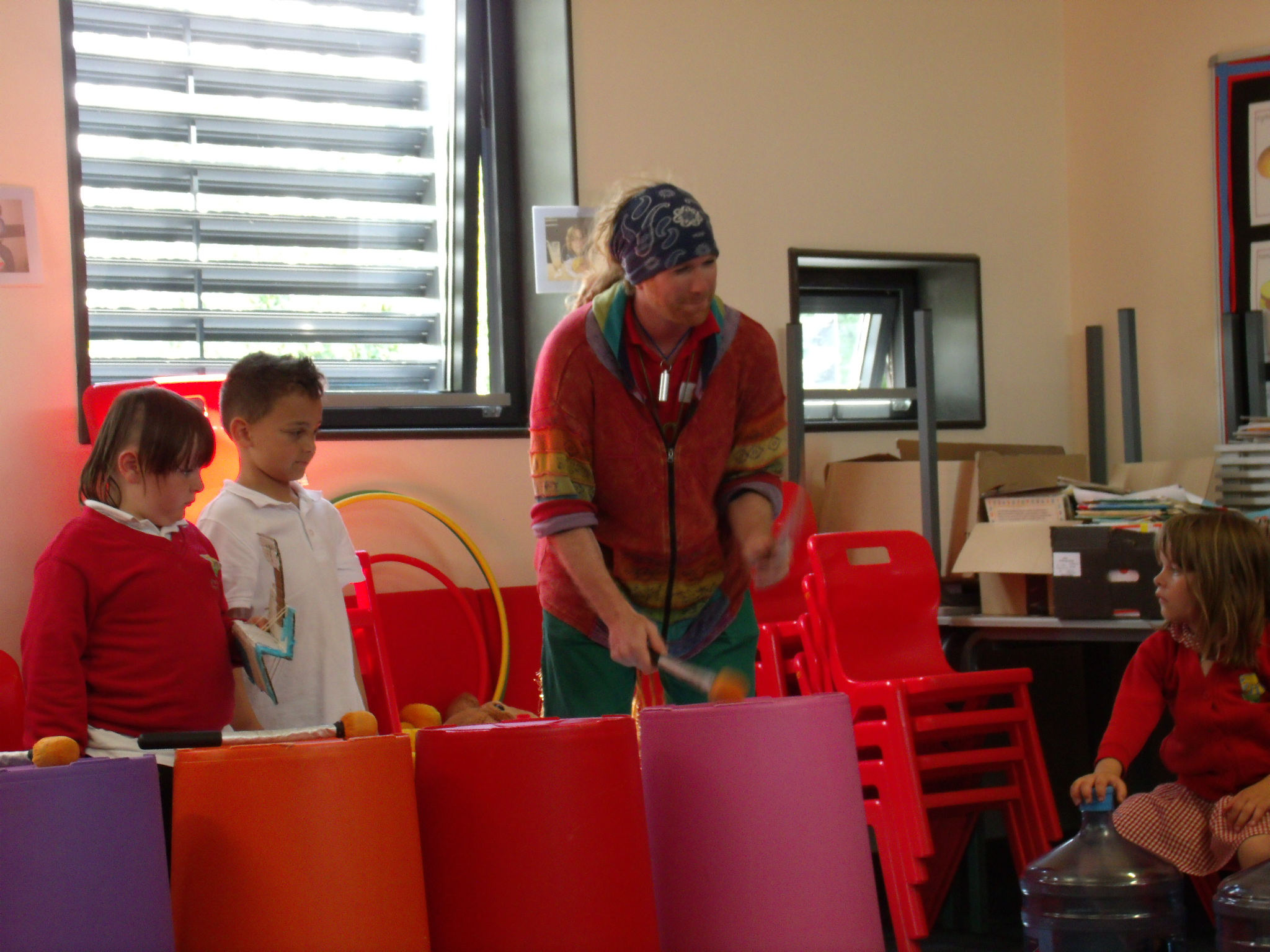 Teacher demonstrating how to play musical instruments made out of bins