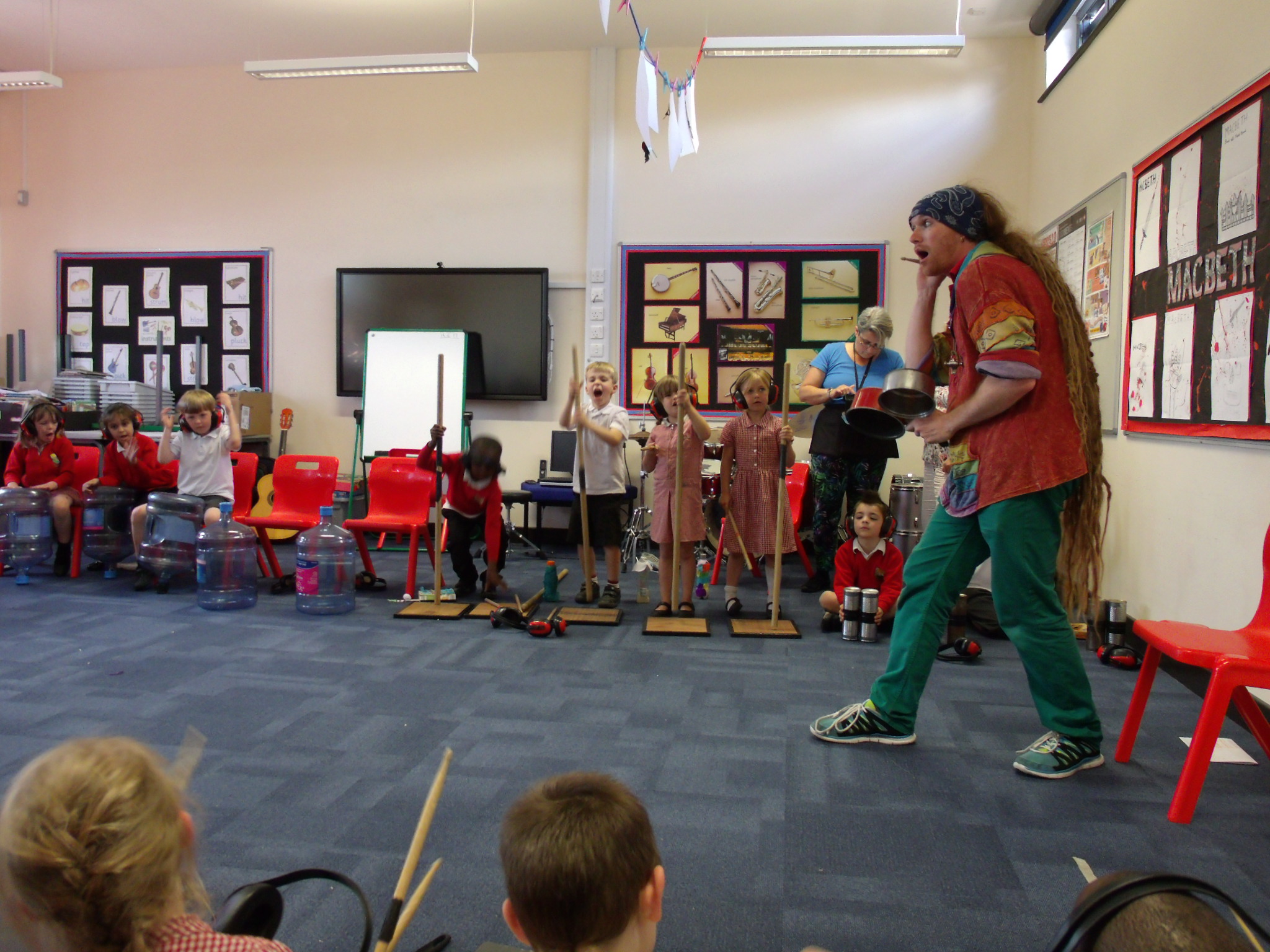 Teach demonstrating how to play musical instruments made out of different objects