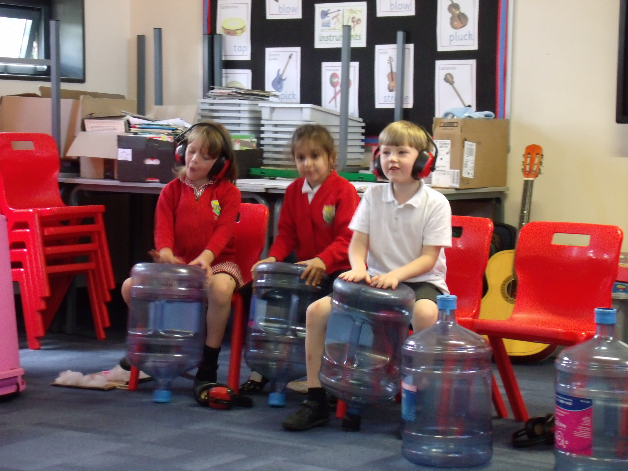School children playing music on large empty bottles