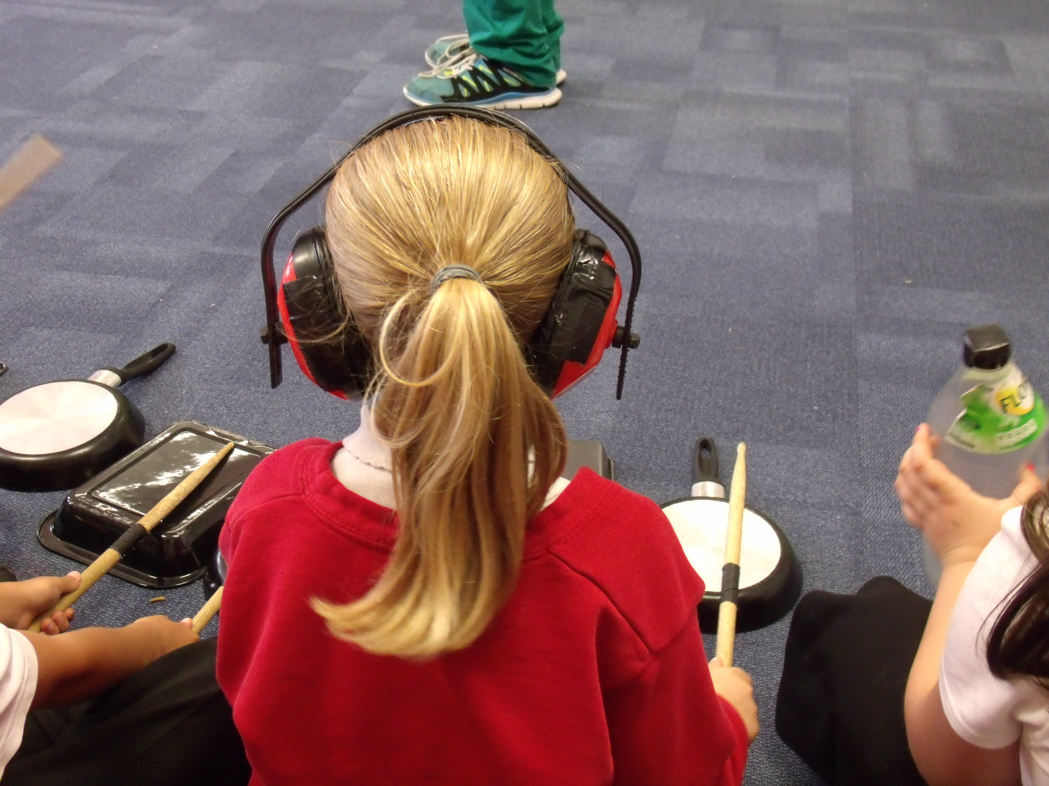 School children playing music on recycled household items