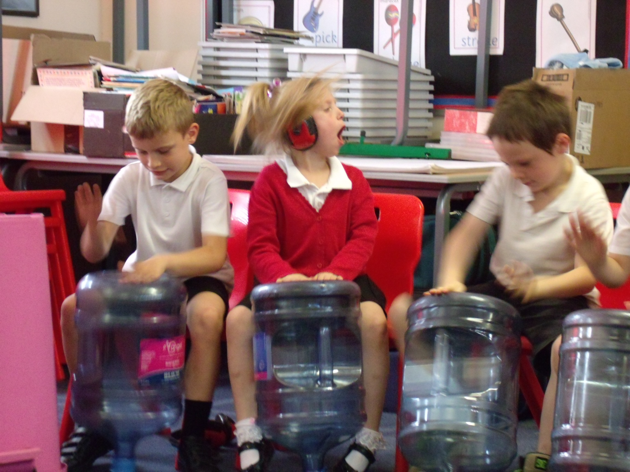 School children playing music on recycled household items