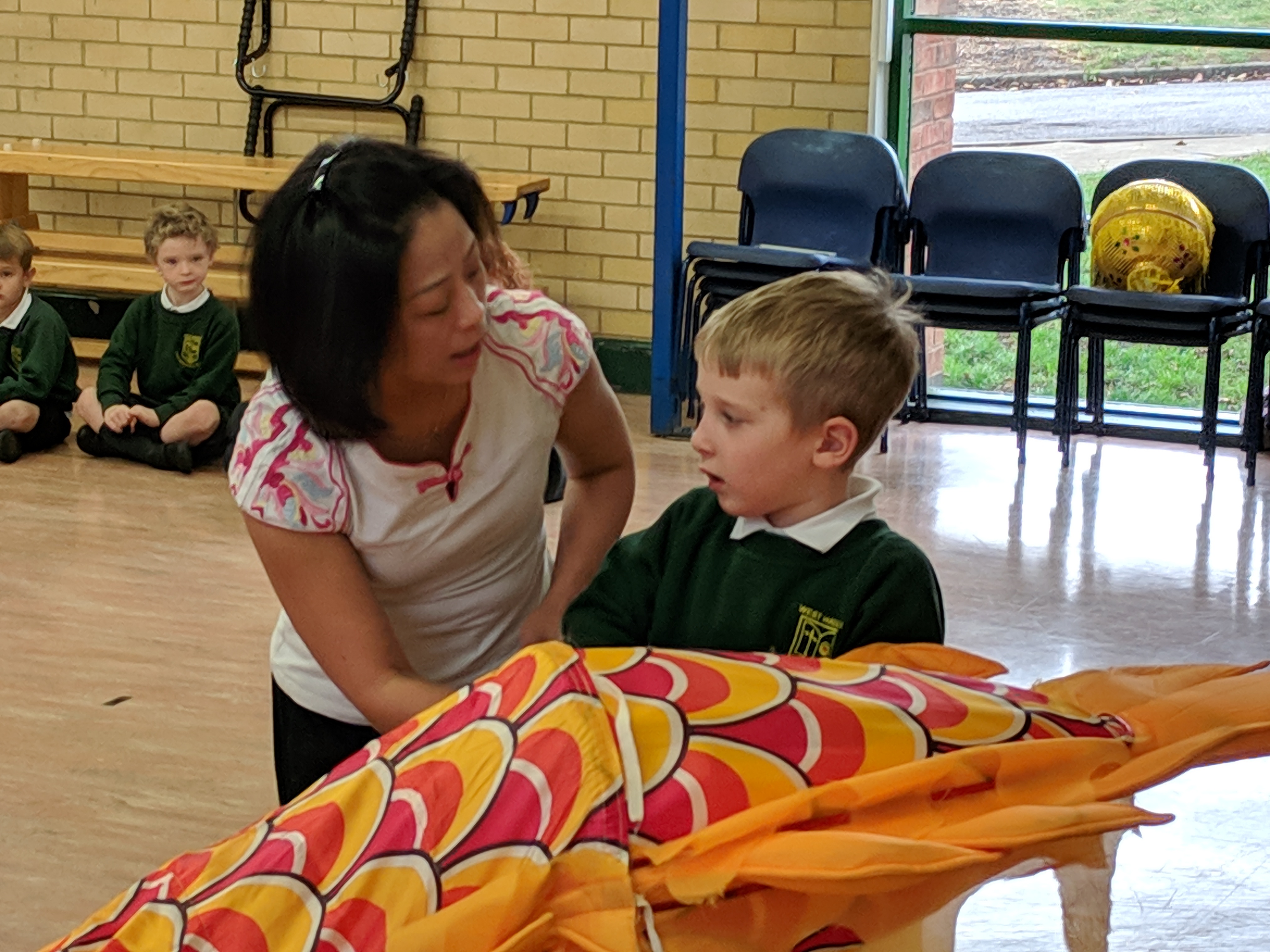 Teacher and child looking at chinese dragon in school hall